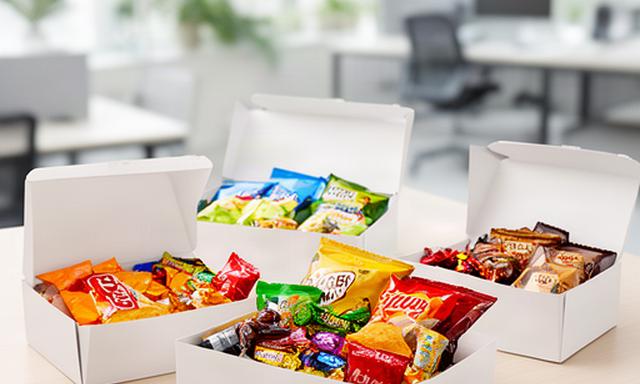Office snack boxes filled with crisps and wrapped sweets on a bright Wigan workplace table