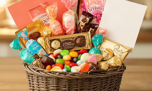 Gift hamper filled with chocolates, wrapped sweets and a handwritten birthday card