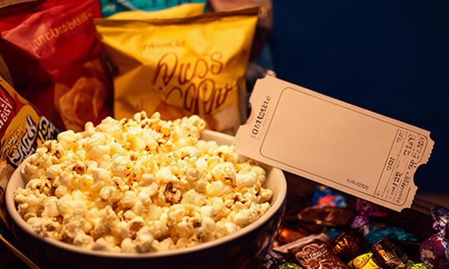 Movie night snack hamper with popcorn, crisps and sweets beside a cinema-style ticket